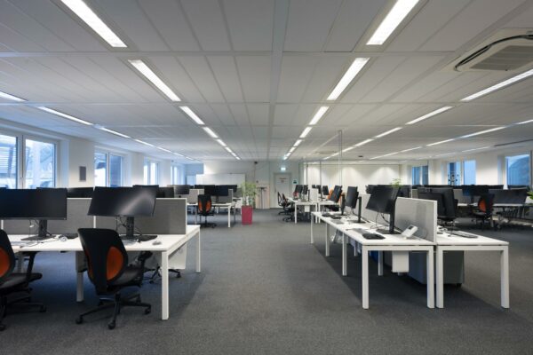 Moderne, ruime kantoortuin met werkplekken en computerschermen aan de Johan Cruijff Boulevard.